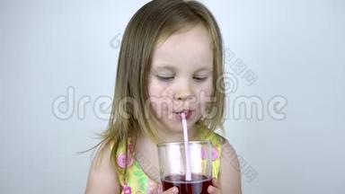 一个三岁的小女孩用吸管从杯子里<strong>喝果汁</strong>。 在白色背景下